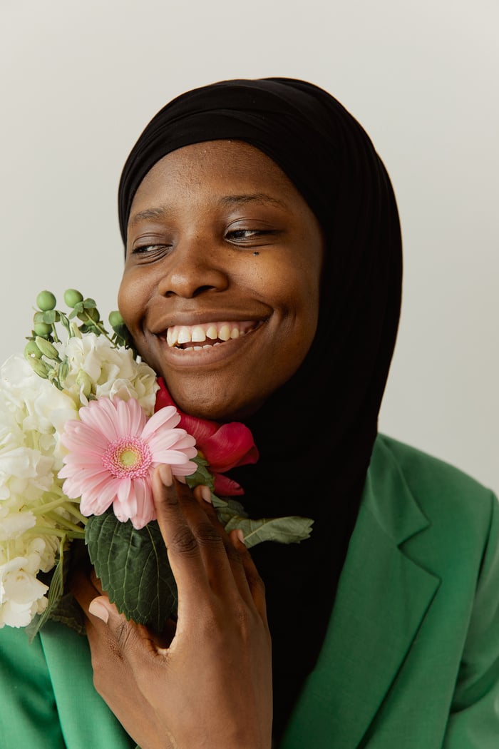 Woman in Green Shirt Holding Pink and White Flower