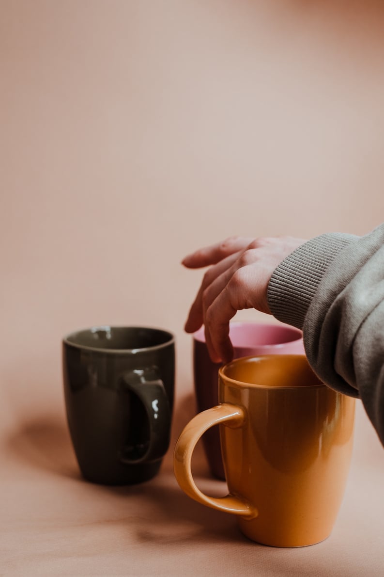 Person Arranging Mugs in a Shelf